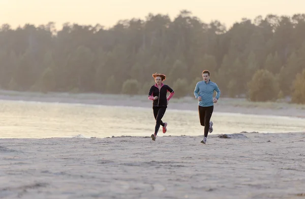 Young man and woman running along the waterfront — Stock Photo, Image