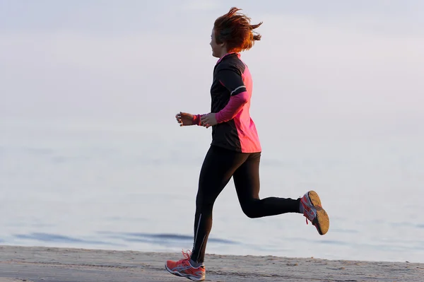 Ung kvinne løper langs sjøsiden – stockfoto