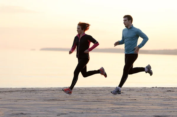 Young man and woman running along the waterfront — Stock Photo, Image