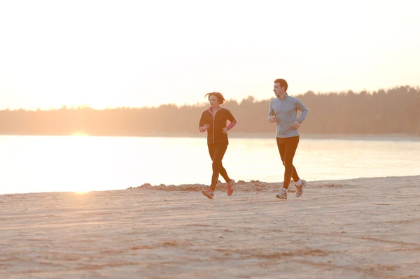 Young man and woman running along the waterfront — Stock Photo, Image