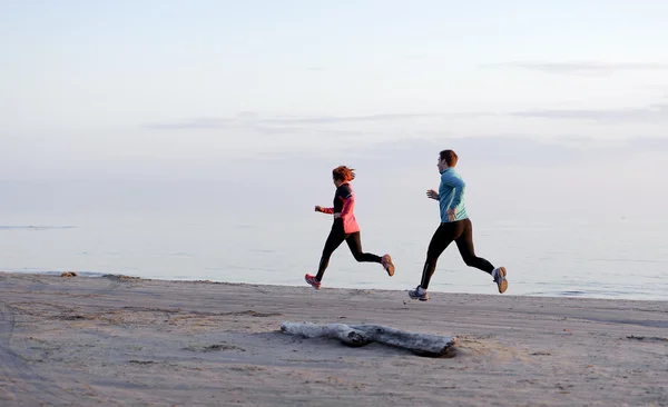 Young man and woman running along the waterfront — Stock Photo, Image