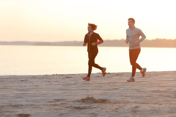 Young man and woman running along the waterfront — Stock Photo, Image