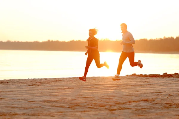 Young man and woman running along the waterfront — Stock Photo, Image