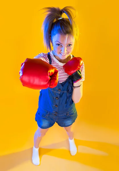 Funny fitness woman with boxing gloves, isolated on yellow