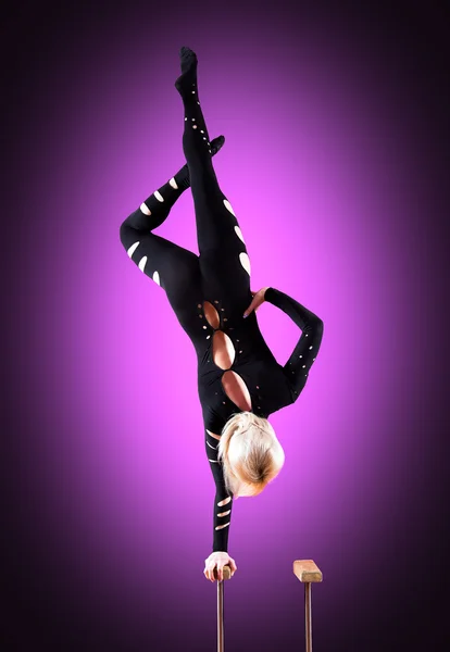 Circus acteur staande op de hand op een paarse achtergrond — Stockfoto