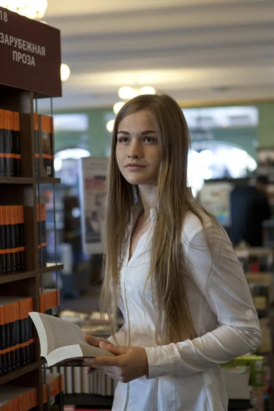 Jovencita elige un libro en una librería — Foto de Stock