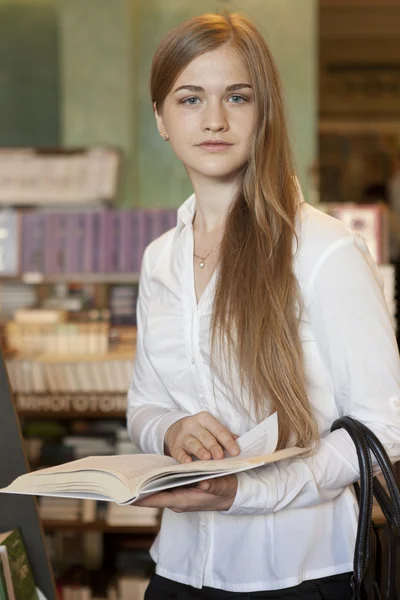 Junges Mädchen sucht sich Buch in Buchhandlung aus — Stockfoto