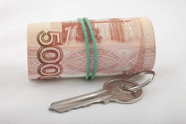 Schlüssel zur Wohnung, die neben einem Bündel Geld liegt — Stockfoto