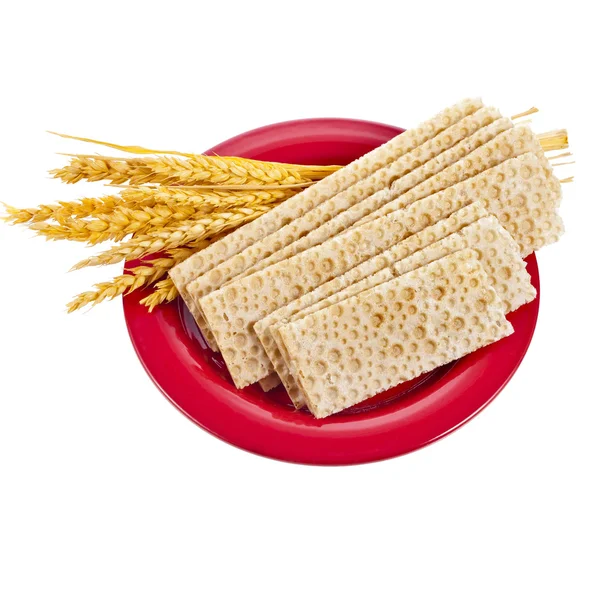 Pan de grano y espigas de trigo que yacen en la placa roja aisladas sobre fondo blanco —  Fotos de Stock