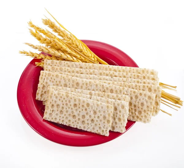곡물 빵과 흰색 배경에 고립 된 빨간 접시에 누워 밀의 귀 — 스톡 사진