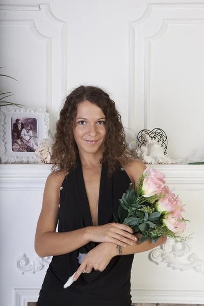 Retrato de una chica con un ramo de rosas junto a la chimenea — Foto de Stock