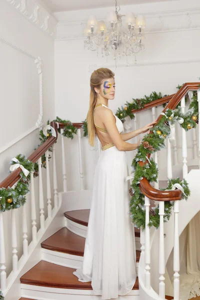 Портрет девушки в длинном белом платье, стоящей на лестнице — стоковое фото