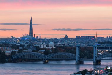 - Rusya. Aziz Petersburg. Neva boyunca uzanan Finlyandsky demiryolu köprüsü, Alexander Nevskaya Lavra ve Lakhta Merkezi