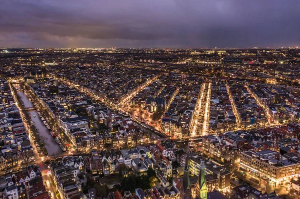 Skyline View of Amsterdam at Night with City Streets and Canals Aerial View