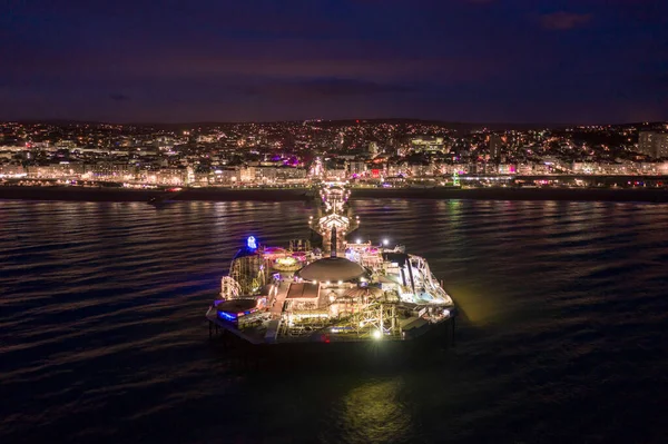 Brighton Seafront Palace Pier and Theme Park Illuminated at Night Aerial View