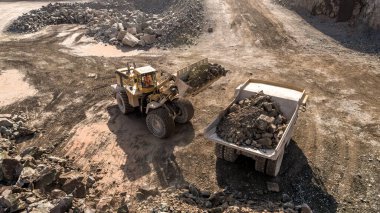 A Digger and Dump Truck Working in a Quarry For Mining clipart