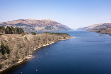 Dağ manzaralı bir gölde büyük bir grup kanocu.