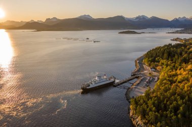 Norveç 'te bir feribot gün doğumunda bir fiyort limanına yanaşıyor.