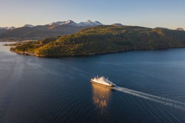 Norveç 'te bir feribot gün doğumunda bir fiyort limanına varıyor.