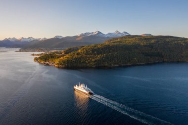 Gün doğumunda fiyorttan geçen bir Norveç feribotu.