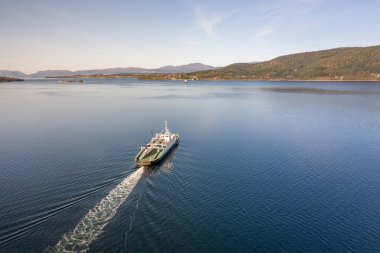 Gün doğumunda fiyorttan geçen bir Norveç feribotu.