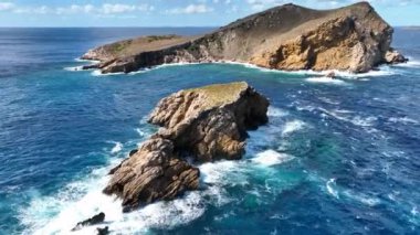 Bir adanın sarp kıyılarında kayalara çarpan dalgalar