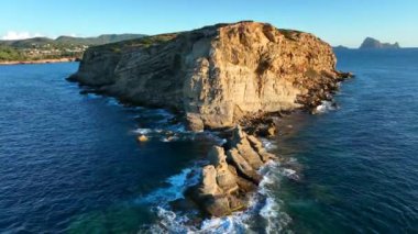 Gün batımında ada, dalgalar kıyı hava manzarasına çarpıyor.