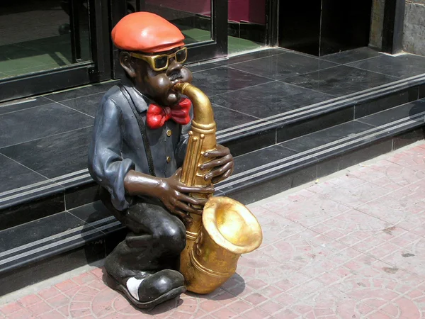 Spela ett instrument av karaktär skulptur framför en restaurang — Stockfoto