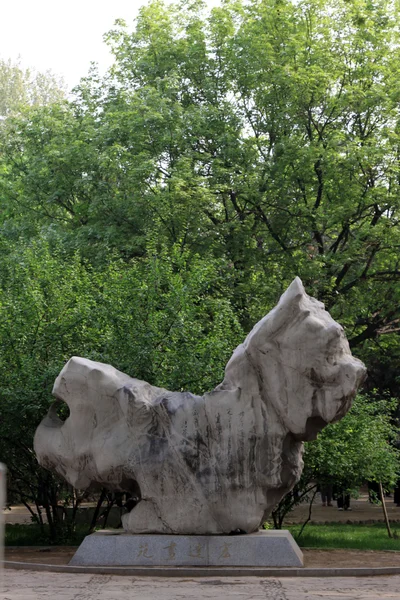 Green trees and stone carving works in a park — Stock Photo, Image