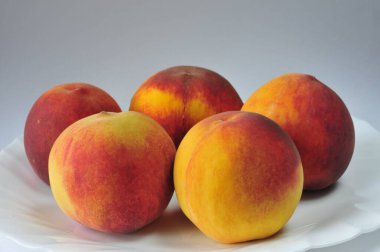 Beyaz bir tabakta parlak, sulu şeftaliler