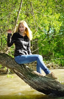 kurumuş ağaç üzerinde oturan sarışın genç kadın