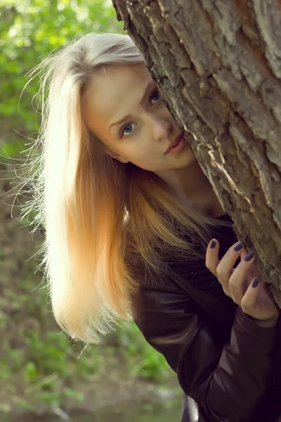 Belle jeune femme regardant hors d'un arbre — Photo