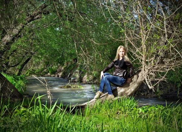 Jonge vrouw zitten op uitgedroogd boom — Stockfoto