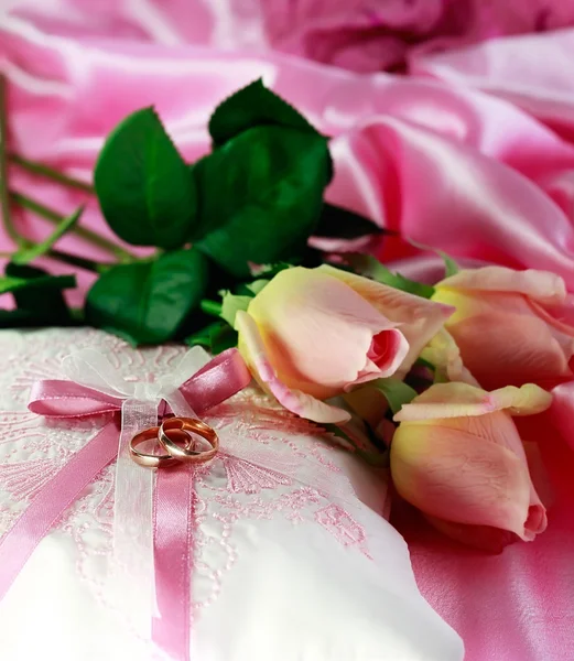 Anillos de oro de boda en una almohada con rosas — Foto de Stock