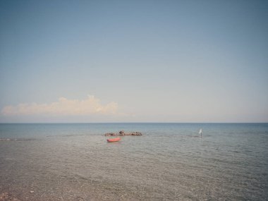 Yunanistan 'ın küçük kayaları, teknesi ve bayrağıyla deniz ufuğu manzarası