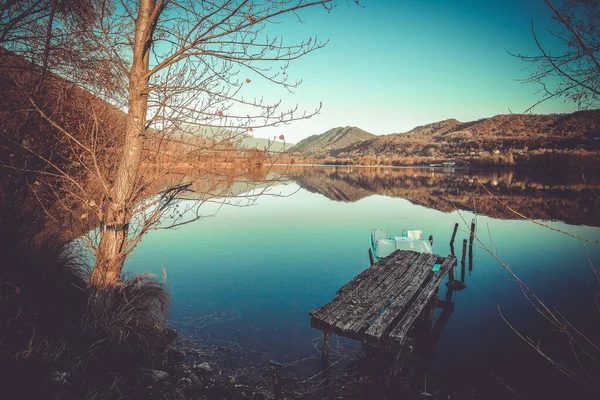 Ancient wooden mooring on the shore of a lake at sunset. Vintage effect photo — 图库照片