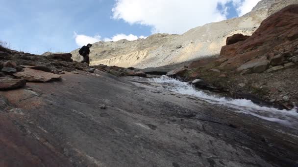 Горный альпинист, спускающийся вдоль высокогорного ледникового ручья — стоковое видео
