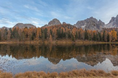 Dolomite tepeleri ve sonbahar renkli ormanlar göl sularını yansıtıyor.