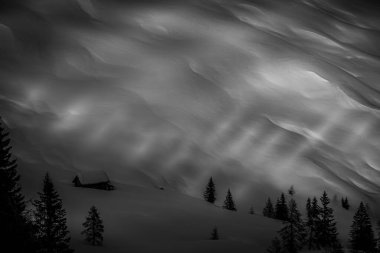 İzole edilmiş kulübenin siyah ve beyaz efekti hafif karlı yamaçta -