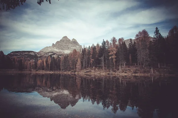 Reflection of autumn larches and dolomitic peaks lake. Vintage effect photo — Stockfoto