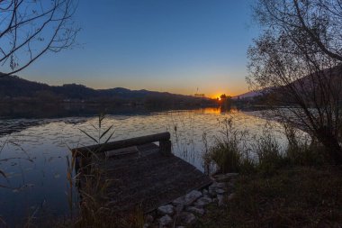 Su zambakları ve eski ahşap iskele ile kaplı gölde güzel bir sonbahar günbatımı.