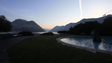 Lugano Gölü 'nde gün doğumu çeşmeli bir bahçeden görülüyor.