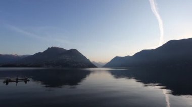 Sonbaharda Lugano Gölü 'nde gündoğumu, sudaki yansımalarla.