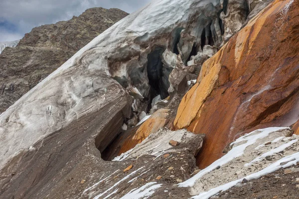 Hål i isen vid foten av Vallelunga glaciär ovanför röda klippor — Stockfoto