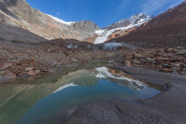 Dağların yansıdığı suları olan buzul cephesinin yakınındaki yüksek dağ göleti. Vallelunga, Alto Adige, İtalya