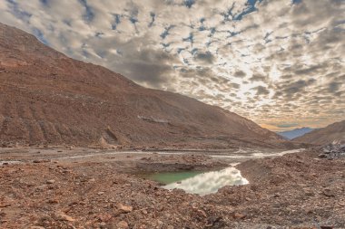 Gün batımında buzul akıntısı ve küçük gölle kaplı Vallelunga Buzulu dili. Küresel ısınma nedeniyle buzullar hızla geri çekiliyor, Alto Adige, İtalya