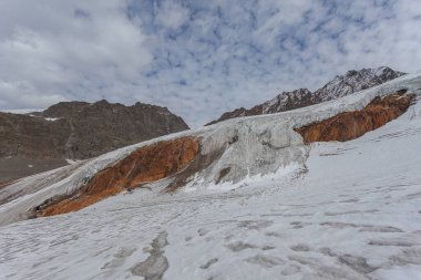 Vallelunga buzulu kızıl dağ kayaları üzerinde akıyor. Küresel ısınma nedeniyle buzullar hızla geri çekiliyor, Alto Adige, İtalya. Dağcıların olduğu popüler bir dağ.