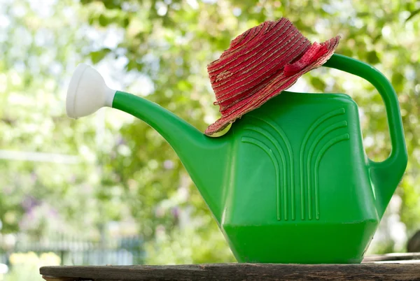 Garden watering can and a hat — Stock Photo, Image