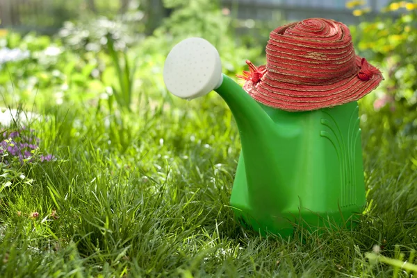 Garden watering can and a hat — Stock Photo, Image