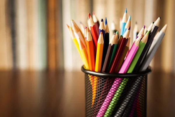 Wire desk tidy full of coloured pencils — Stock Photo, Image